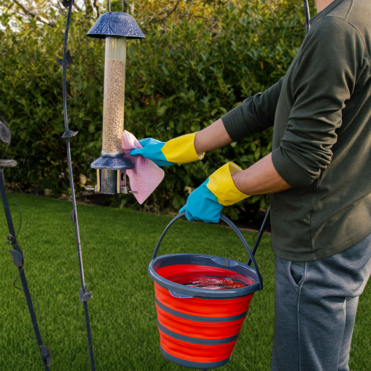 Bird feeder being wiped clean on its pole with the folding bucket of water close at hand (cloth not included)