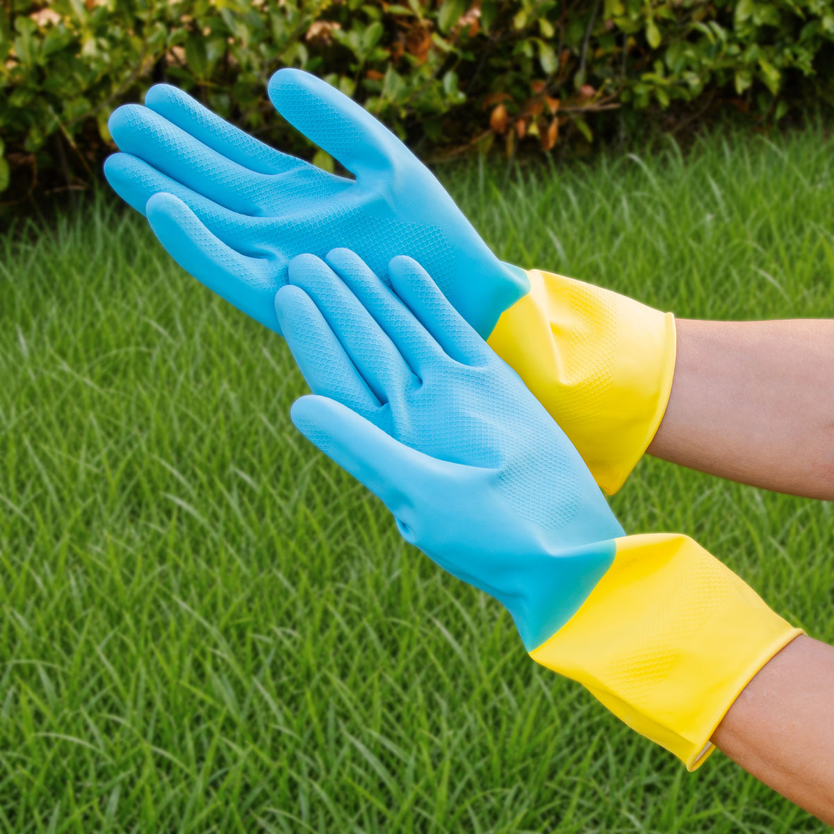 Pair of blue and yellow textured-grip cleaning gloves being worn in the garden